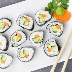 Talerz z sushi z awokado, ogórkiem i marchewką, pałeczki i wasabi.