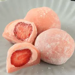 Różowe mochi z truskawkami na szarym talerzu.